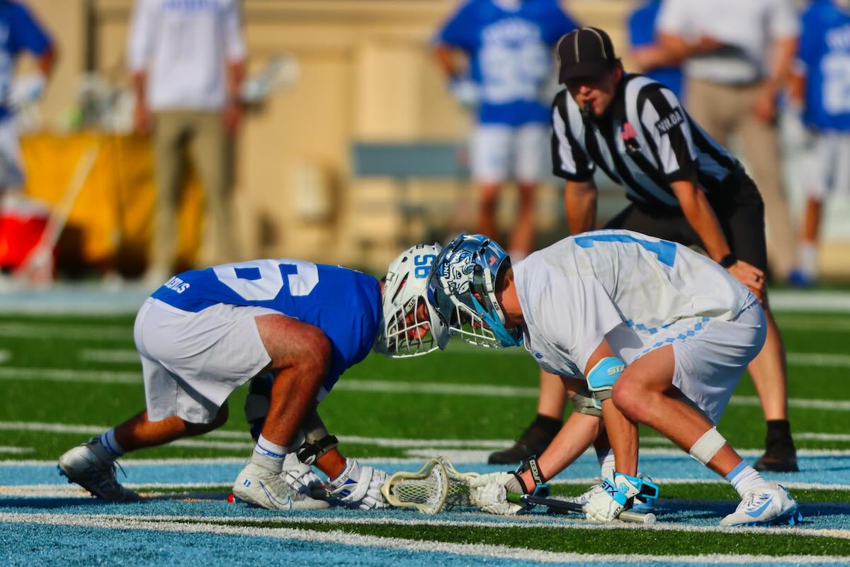 Two lacrosse players on a pitch