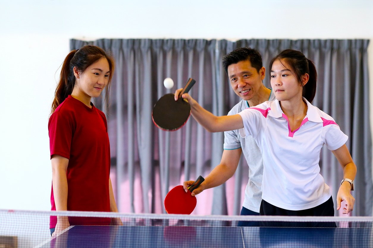 A man and 2 women playing table tennis